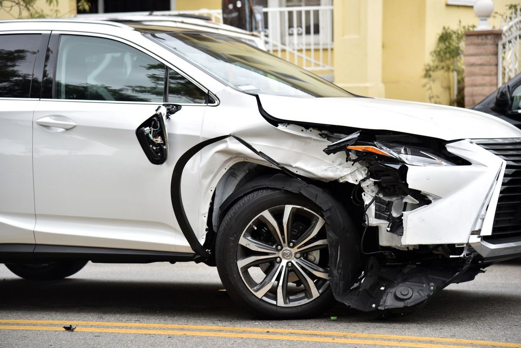 SUV blanco con graves daños por colisión en la parte delantera derecha estacionado en una calle