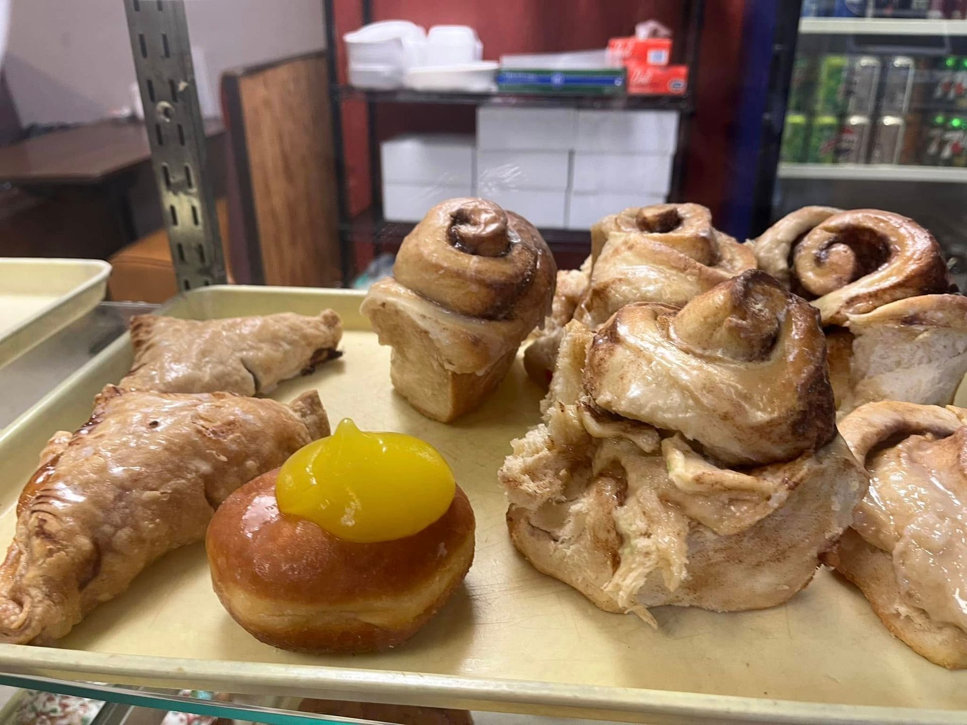 A variety of pastries are on a tray in a bakery.