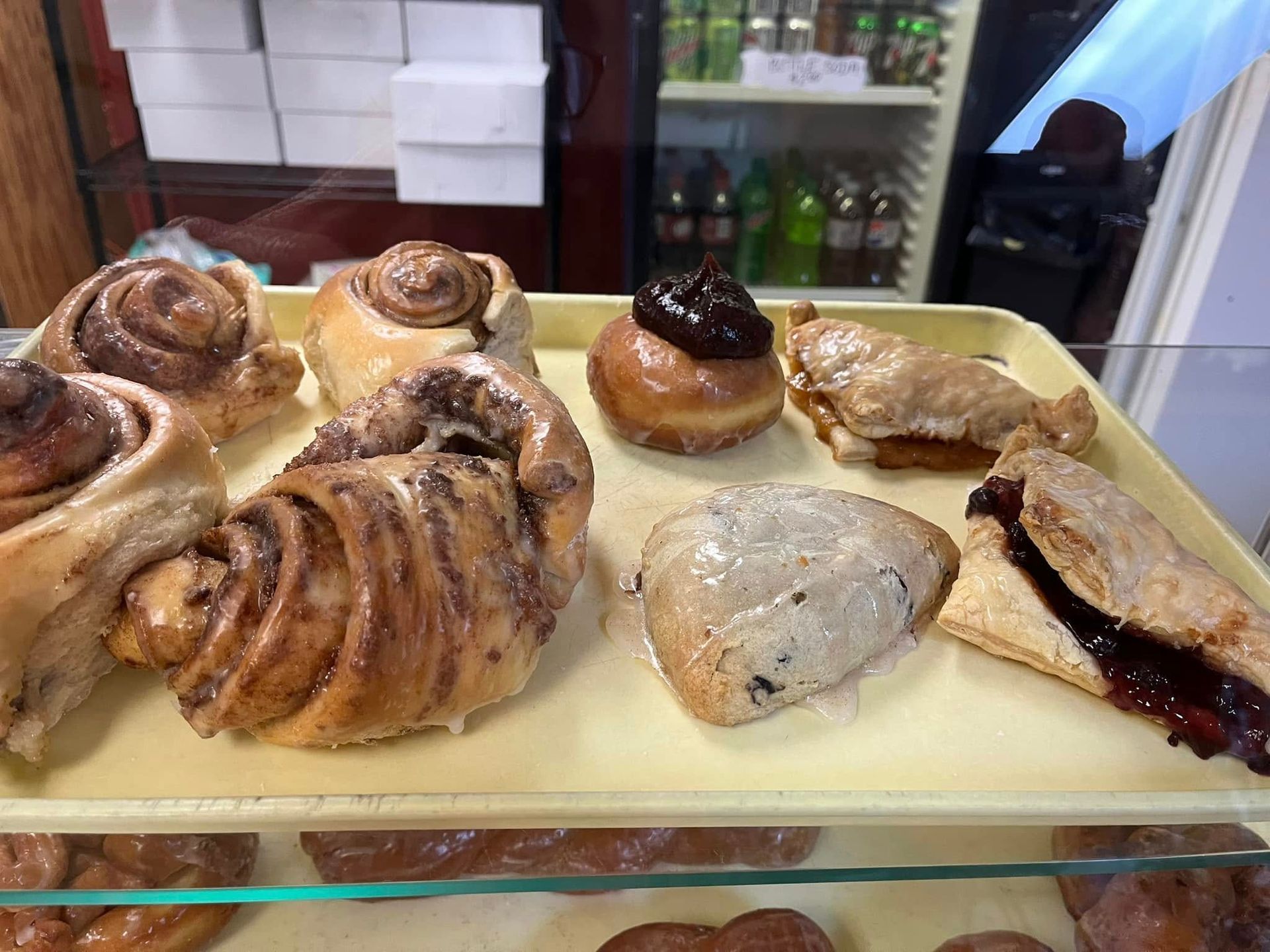 A variety of pastries are on a tray in a bakery.