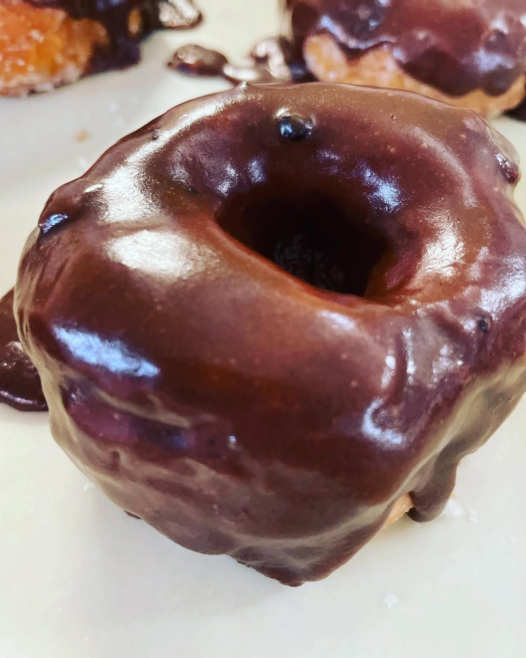 A close up of a chocolate covered donut on a white plate