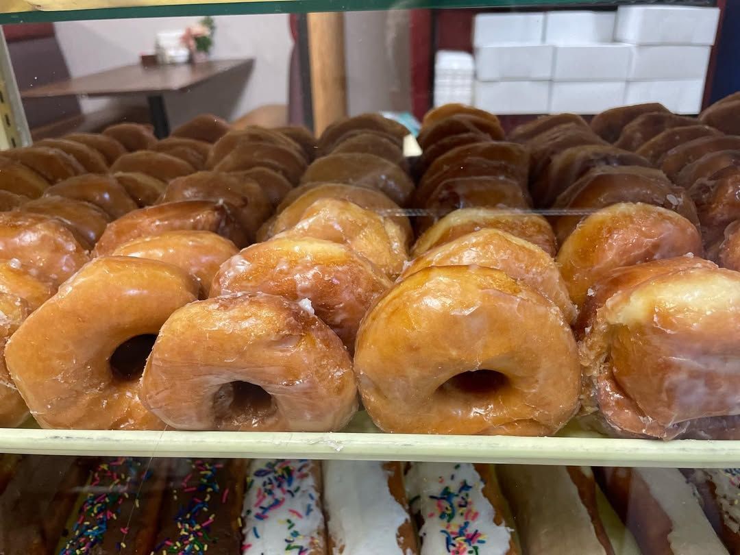 A bunch of donuts are sitting on a shelf in a bakery.