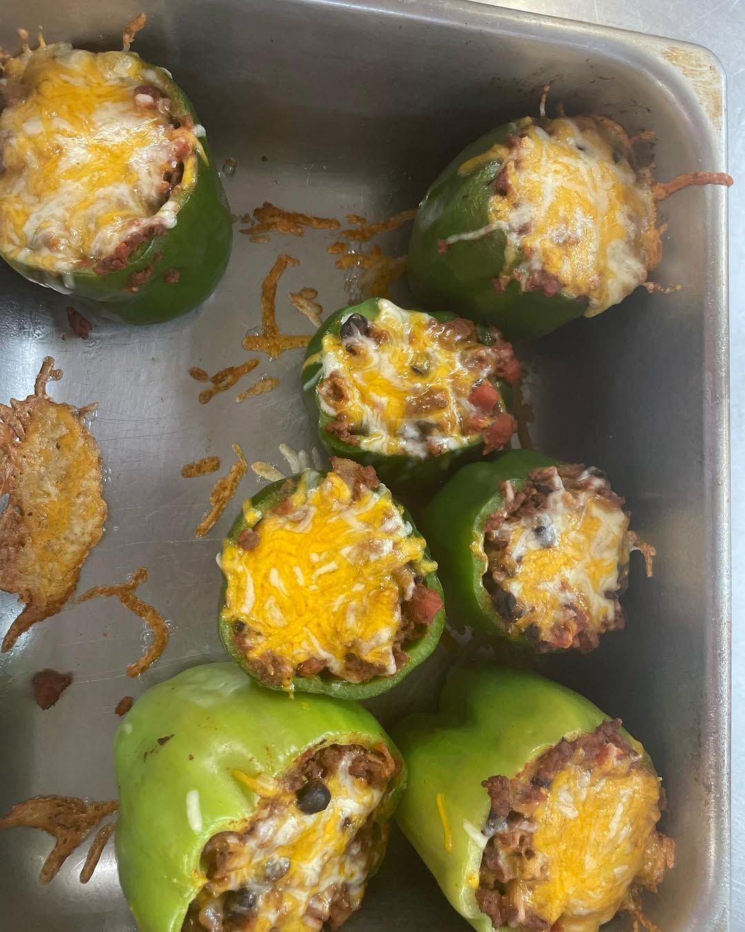 A pan filled with stuffed peppers covered in cheese and meat.