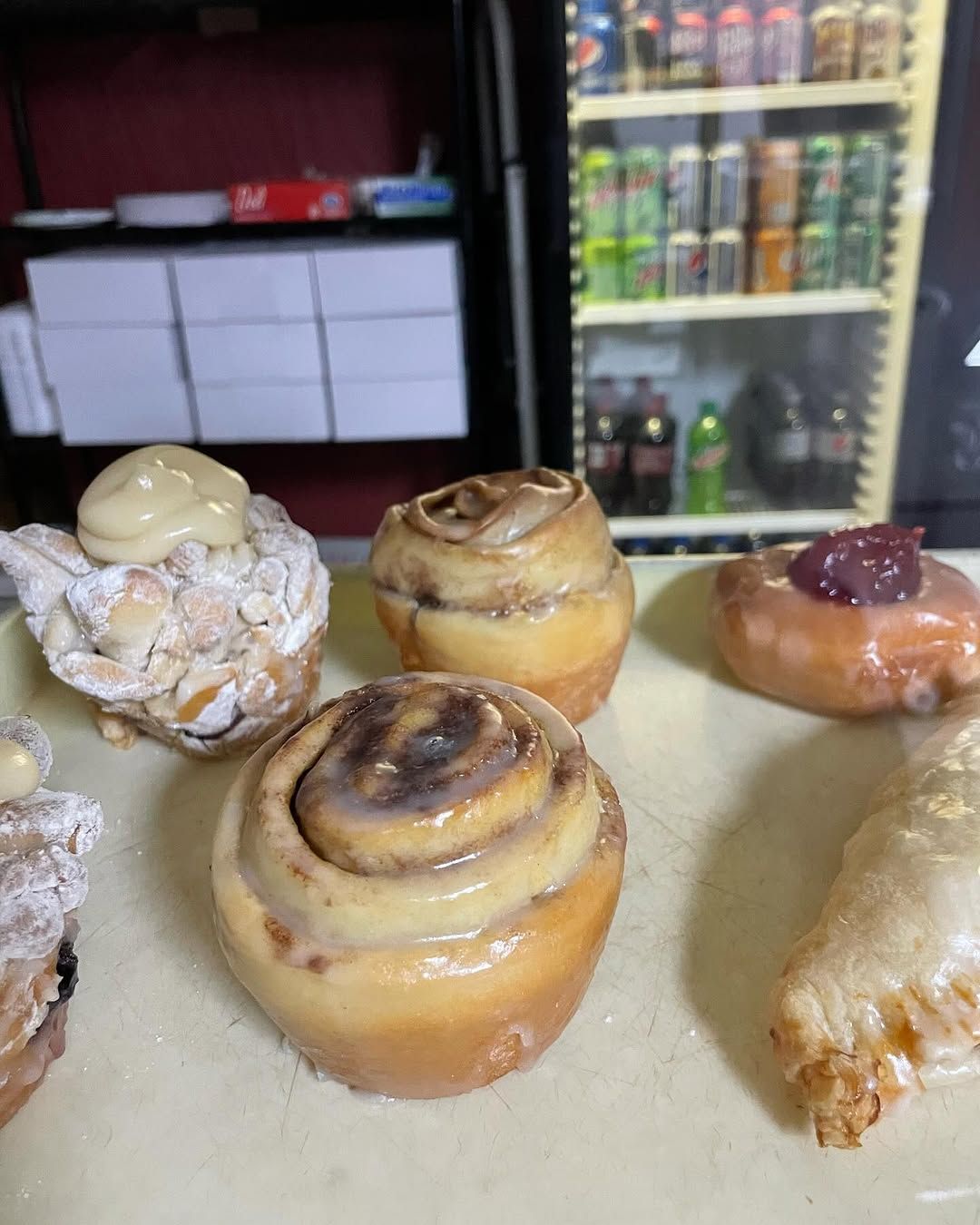 A bunch of pastries are sitting on a table in front of a refrigerator.