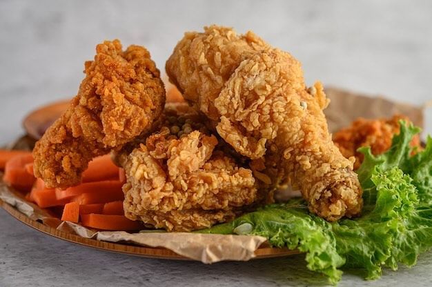 A plate of fried chicken with carrots and lettuce on a table.