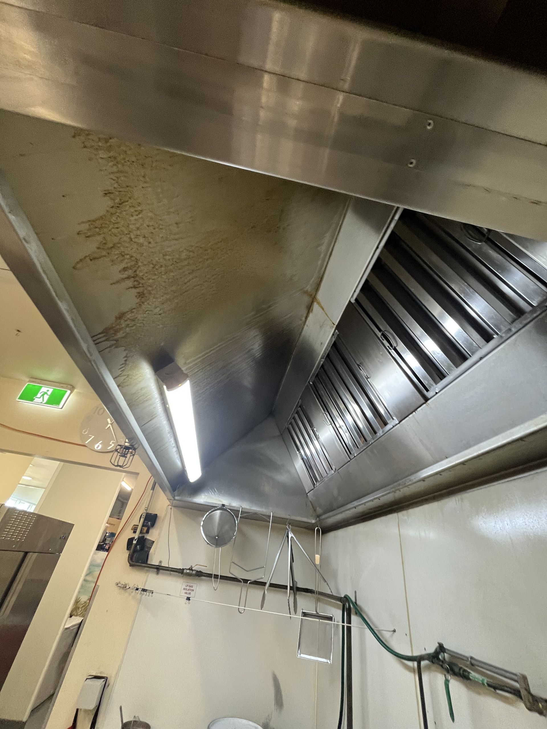 Stainless steel kitchen exhaust hood with visible grease buildup. - DM & MM Services, Exhaust Cleaning, Townsville, QLD.