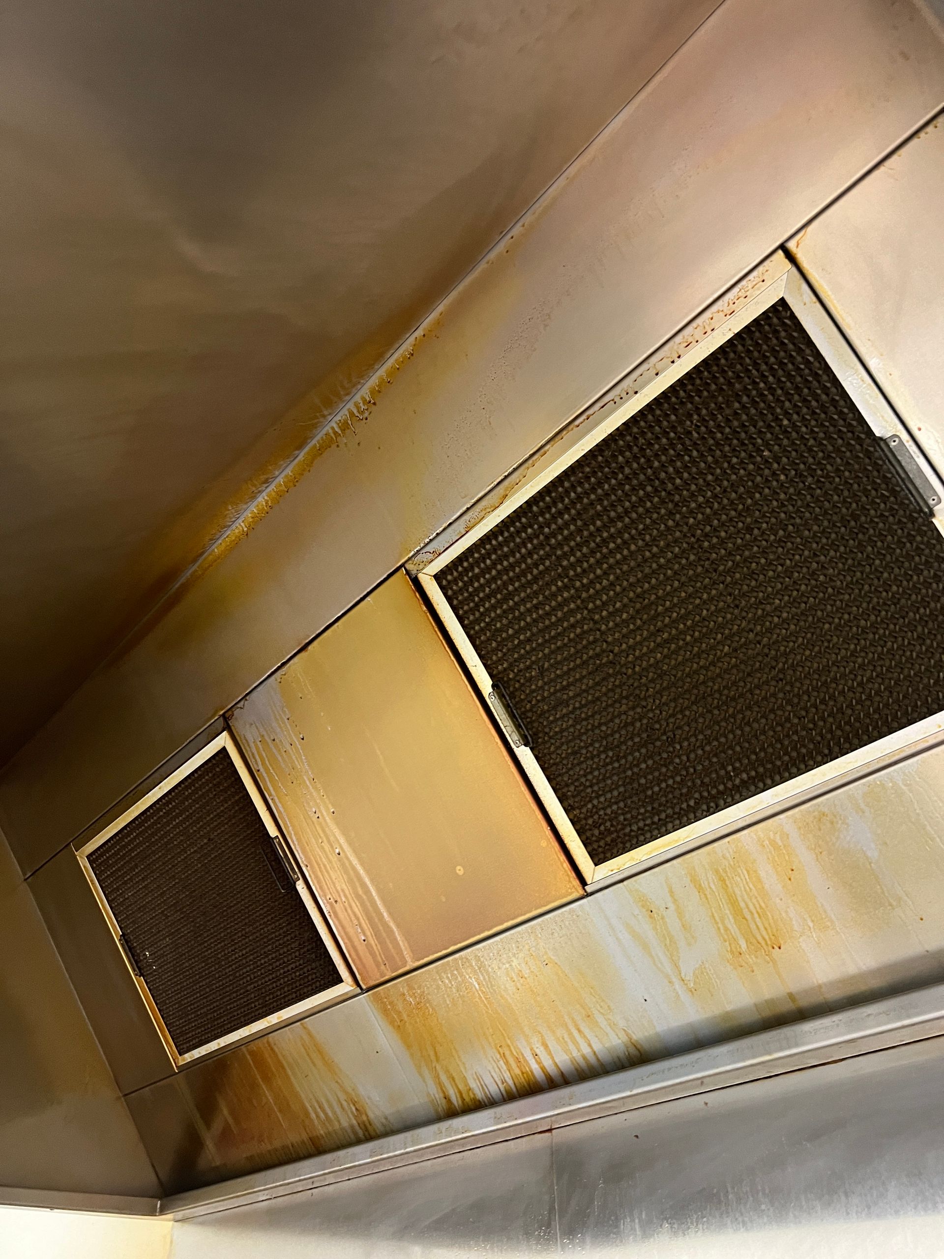 A Close Up Of A Stainless Steel Exhaust Hood With Dirty Filters — DM & MM Services Pty Ltd in Mount Louisa, QLD