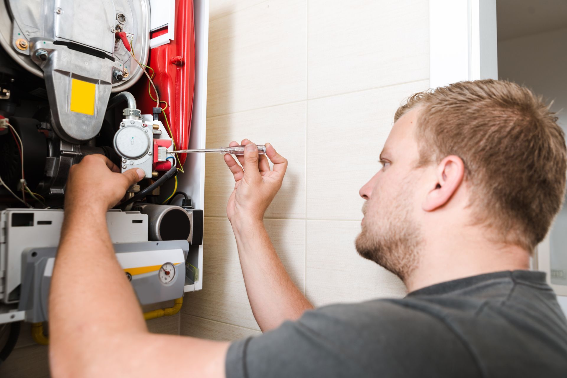Technician using wrench to perform furnace repair on home heating system unit.