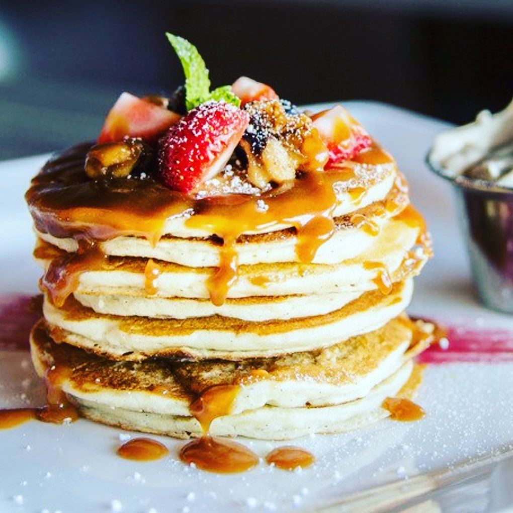A stack of pancakes with caramel sauce and strawberries on top