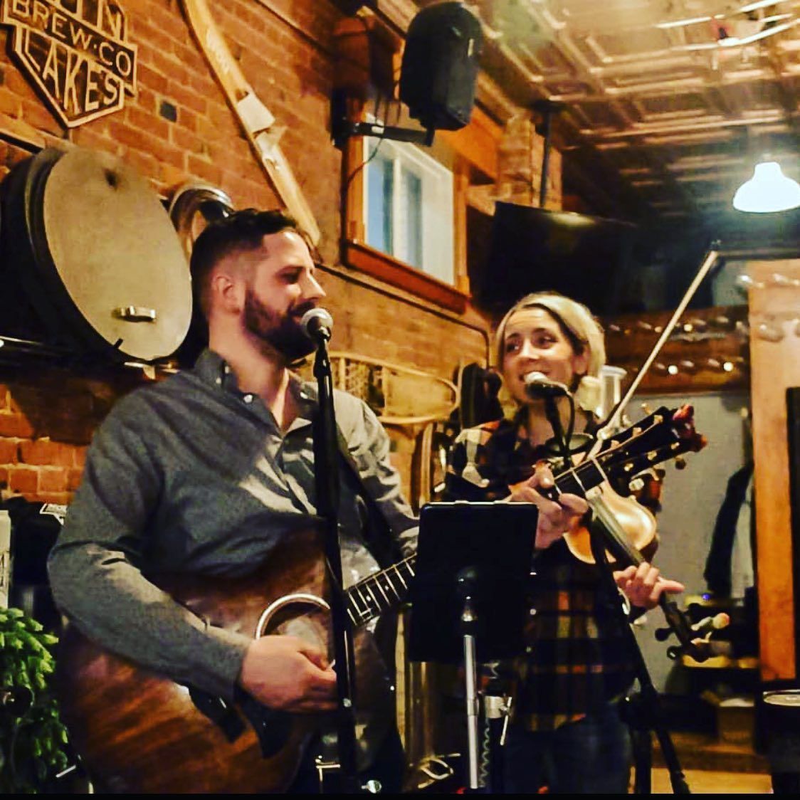 A man singing into a microphone while a woman plays a violin