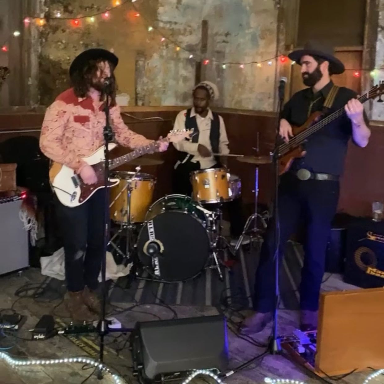 A man in a cowboy hat is playing a guitar in a band