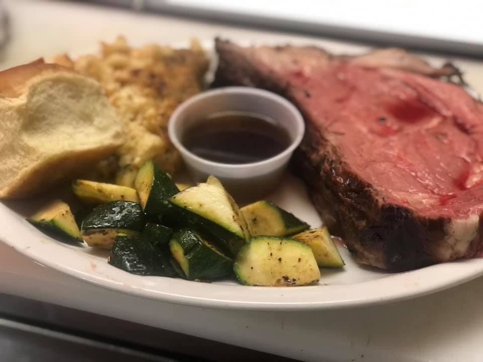 A white plate topped with a large piece of meat and vegetables.