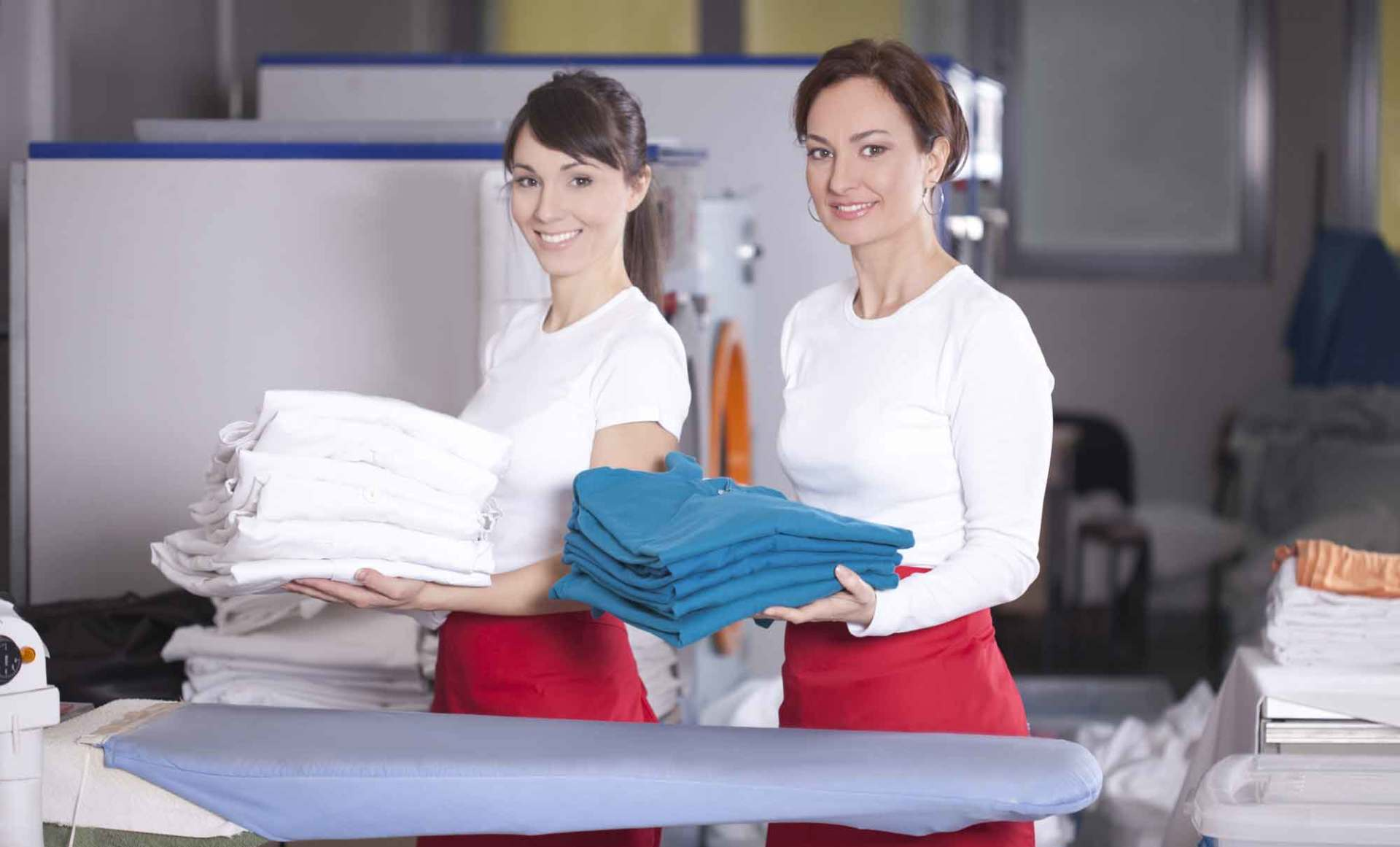 Women with folded clothing front of washing machines