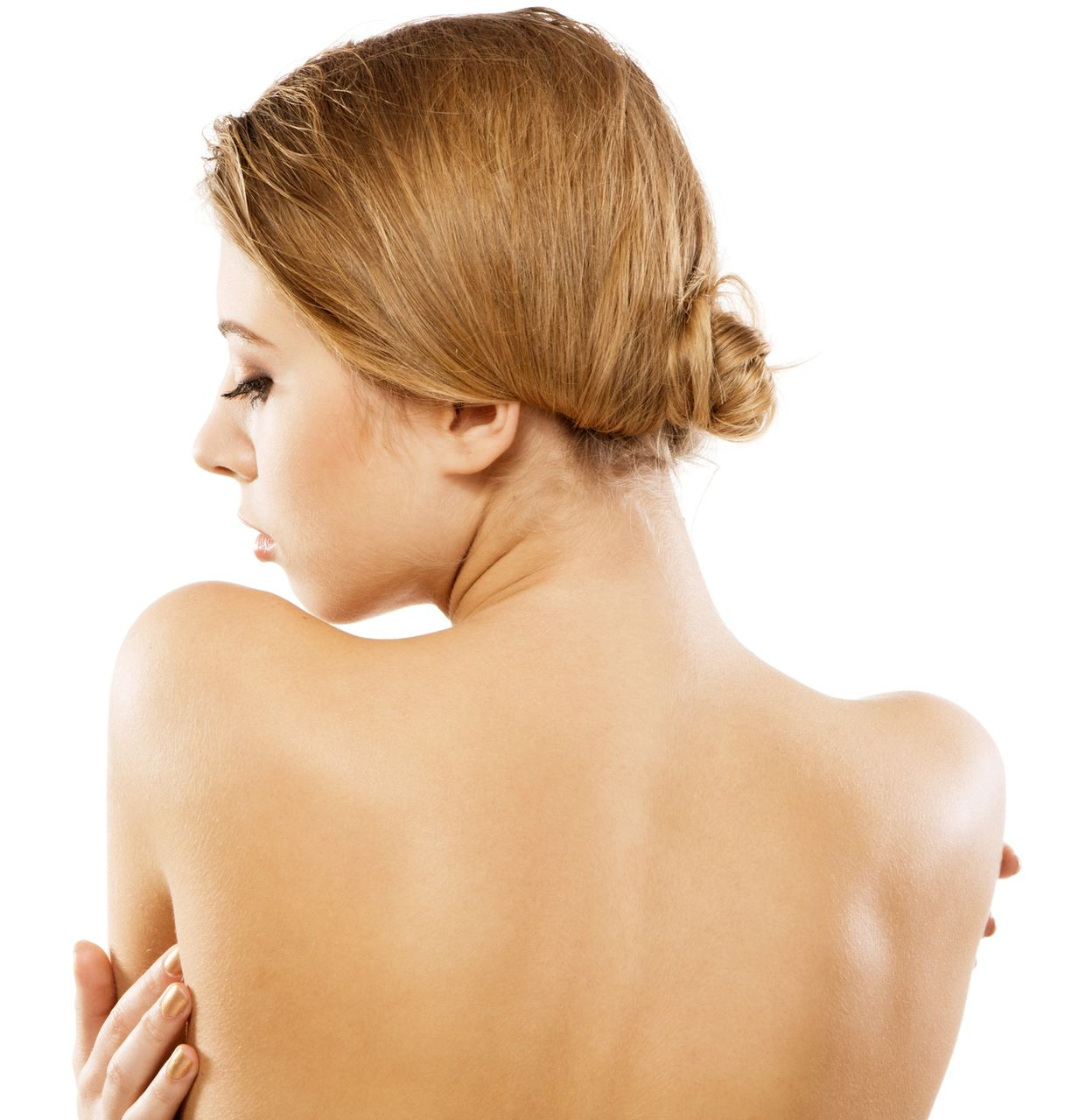 Donna dalla pelle chiara, di spalle alla telecamera, braccia incrociate, capelli raccolti, su sfondo bianco.