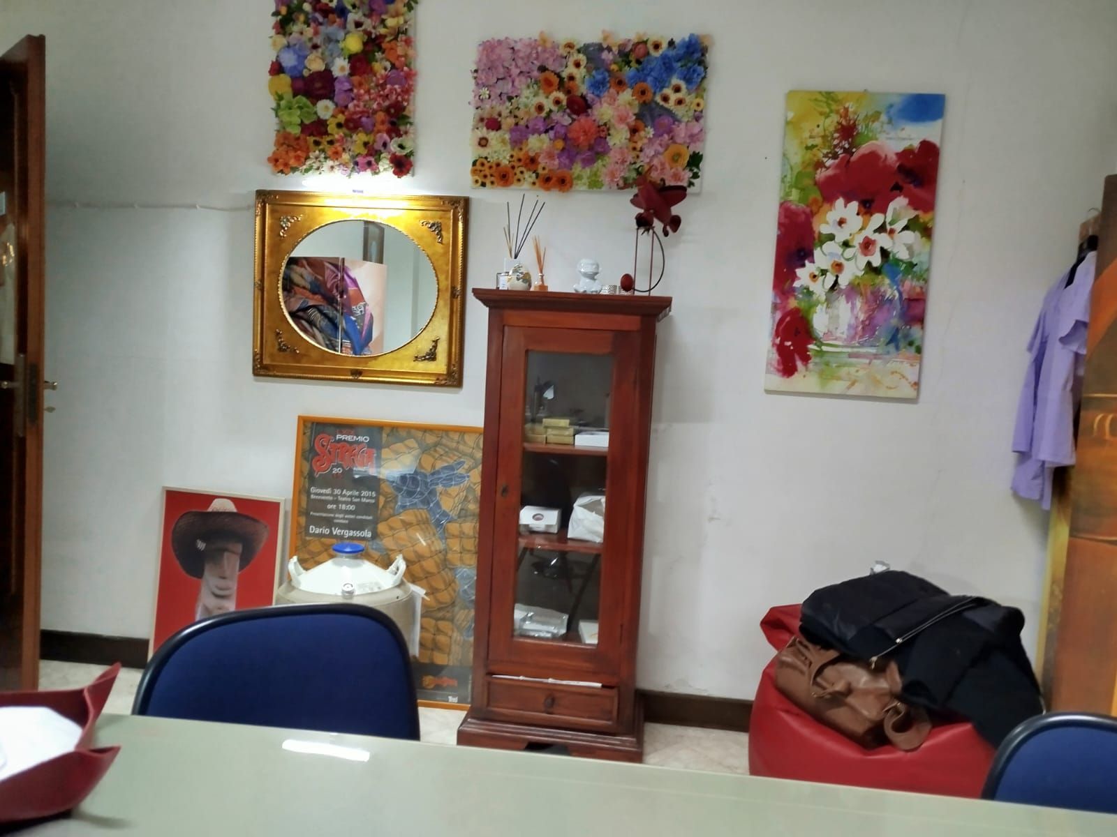 Una stanza con un armadio, un'opera d'arte e un tavolo. Un'opera d'arte floreale colorata è appesa alla parete sopra uno specchio.