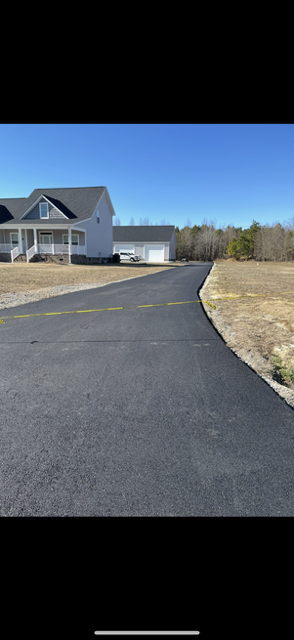 Road workers patching asphalt with shovels and rakes on a paved street.