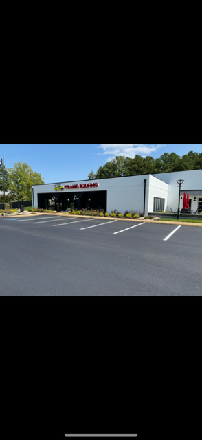 Workers in orange uniforms pouring asphalt from a wheelbarrow onto a road surface.