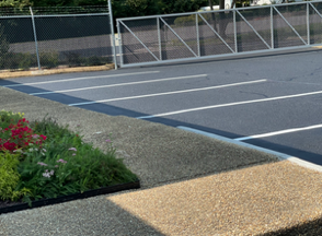 Cracked asphalt road in foreground, blurry residential houses in the background at dusk.