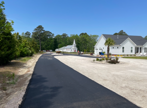 Roller applying sealant to patterned black paving stones; a bucket is in the background.