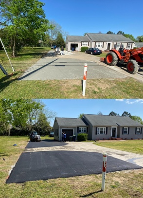 Cracked asphalt road in foreground, blurry residential houses in the background at dusk.