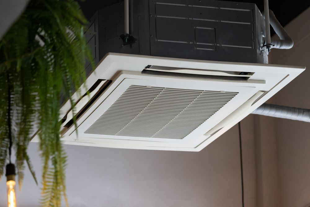 Ceiling cassette air conditioner with vented grille in a room, seen from below