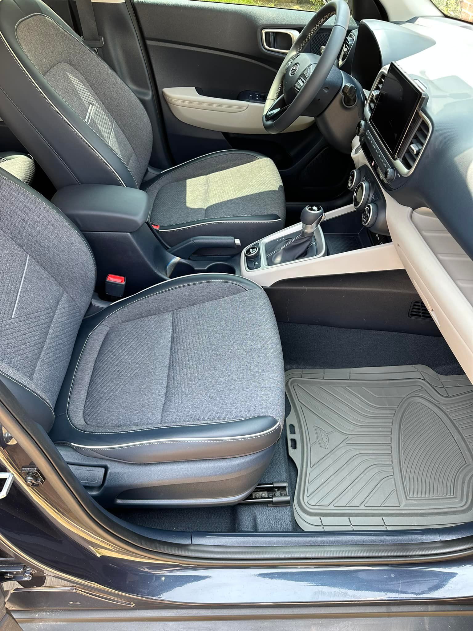 Interior view of a car with gray seats, a gray floor mat, and a black dashboard.