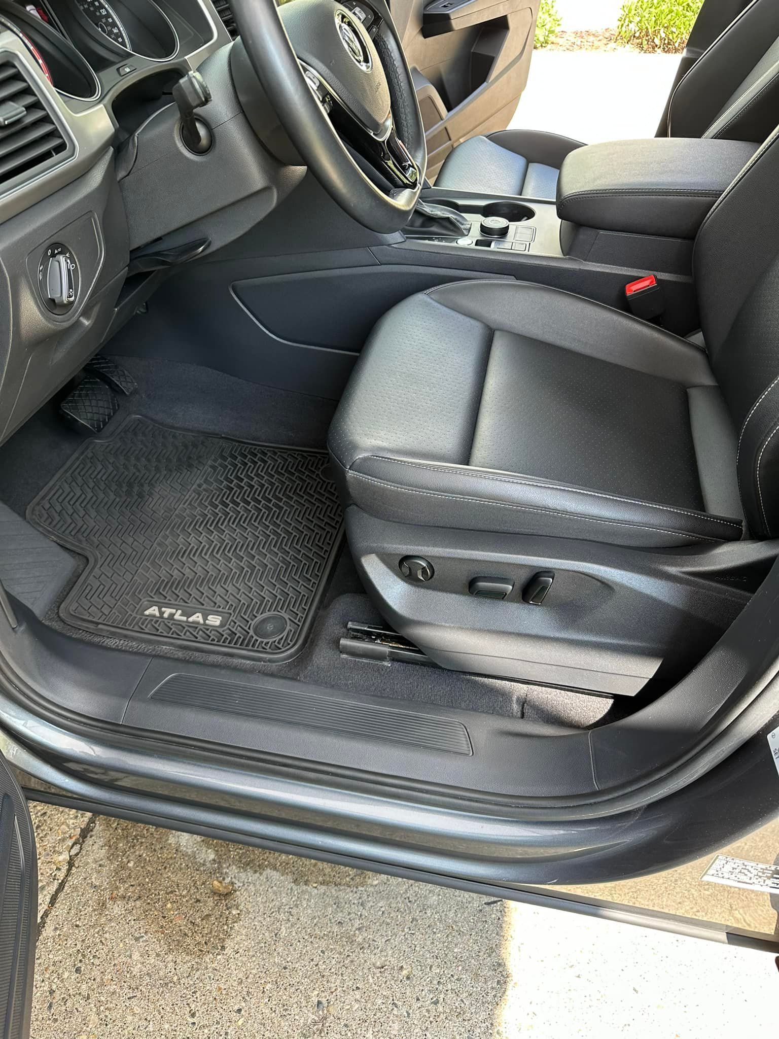 Car interior: black seat, floor mat, steering wheel, dashboard visible.