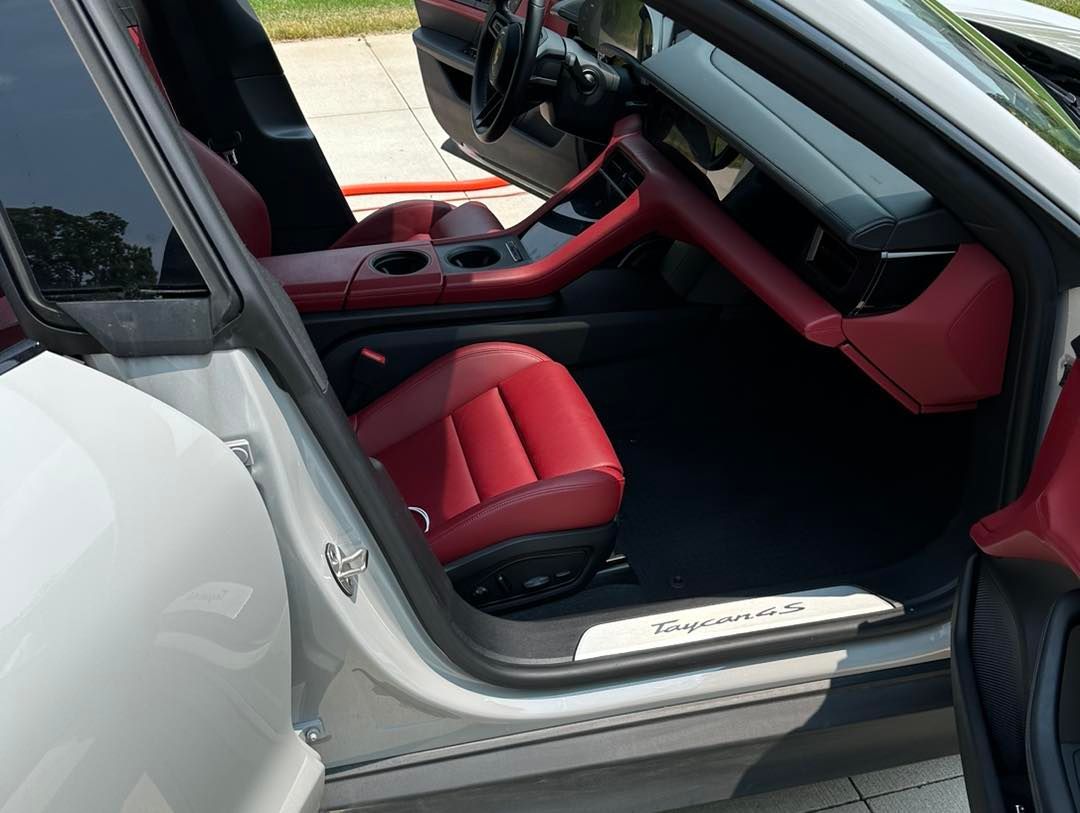 Silver Porsche Taycan interior with red leather seats, door open.