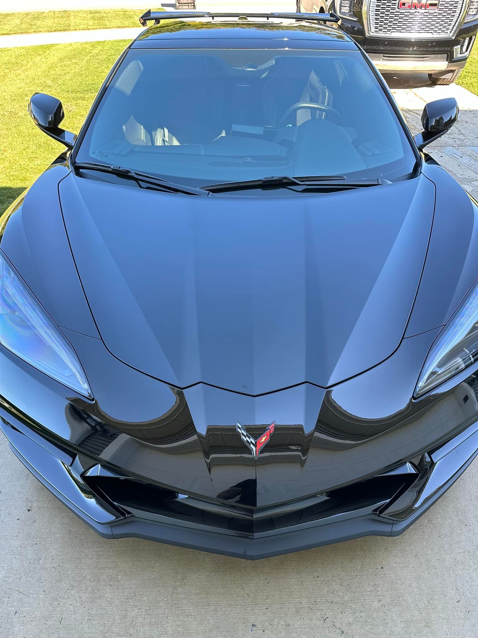 Black Chevrolet Corvette sports car parked on concrete.