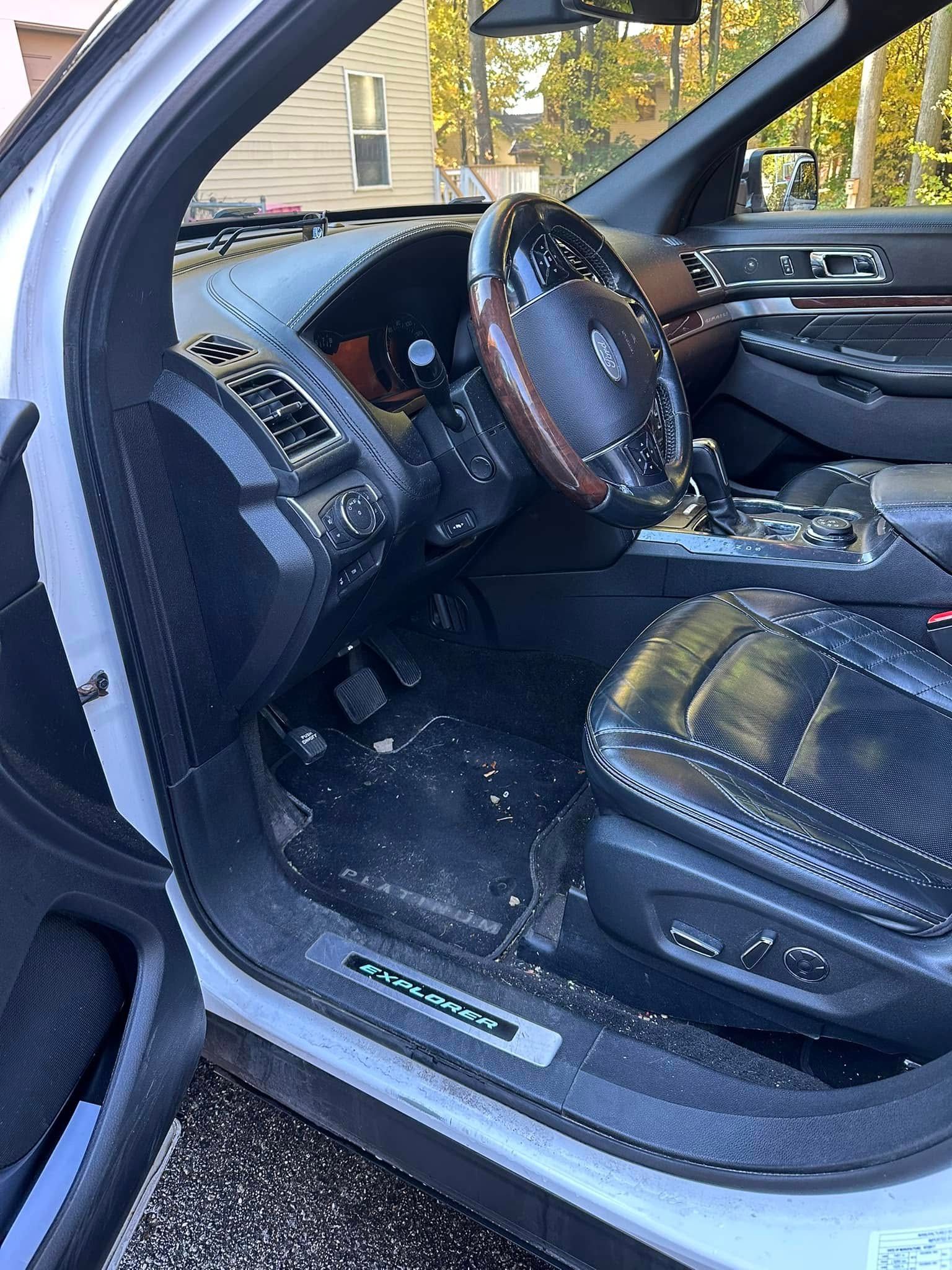 Interior of a white car, showing the driver's side seat, steering wheel, and dashboard.