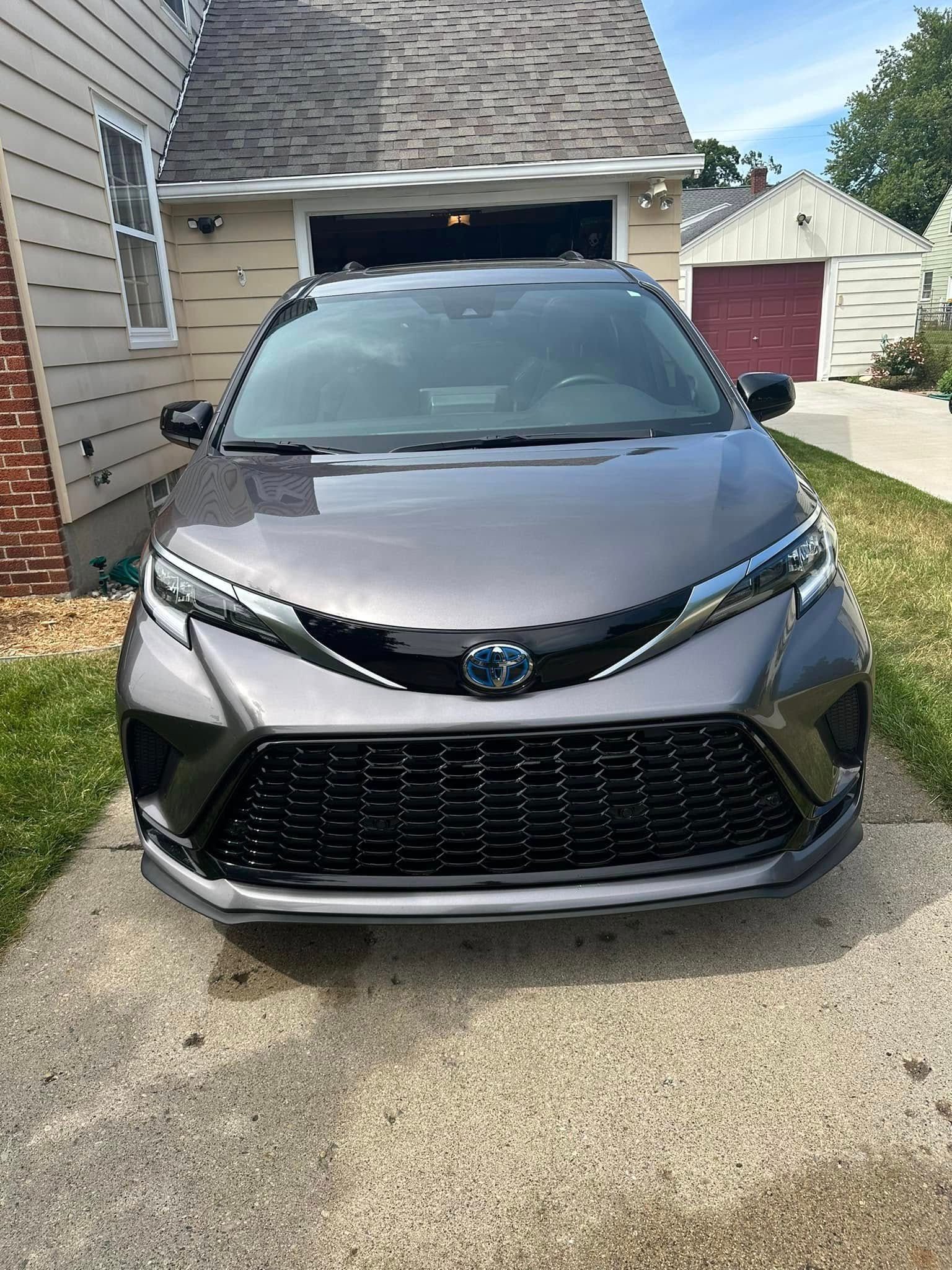 Gray Toyota Sienna minivan parked in a driveway in front of a house and garage.