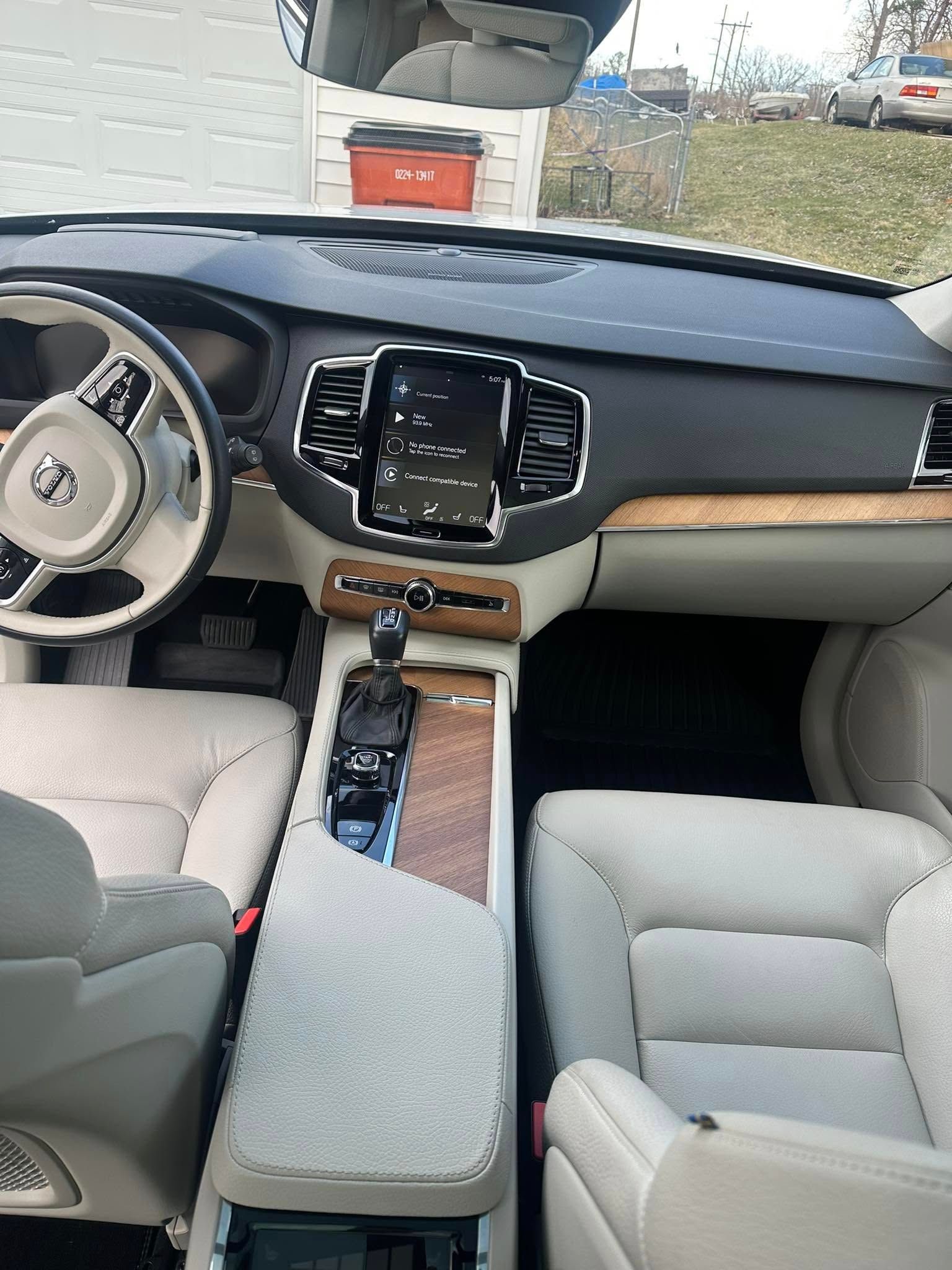 Interior of a beige Volvo SUV. Steering wheel, dashboard, center console, and seats are visible.
