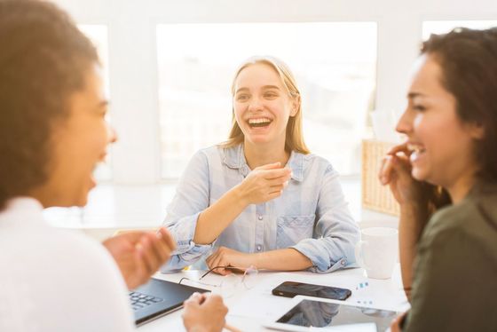 A group of women are sitting at a table laughing.