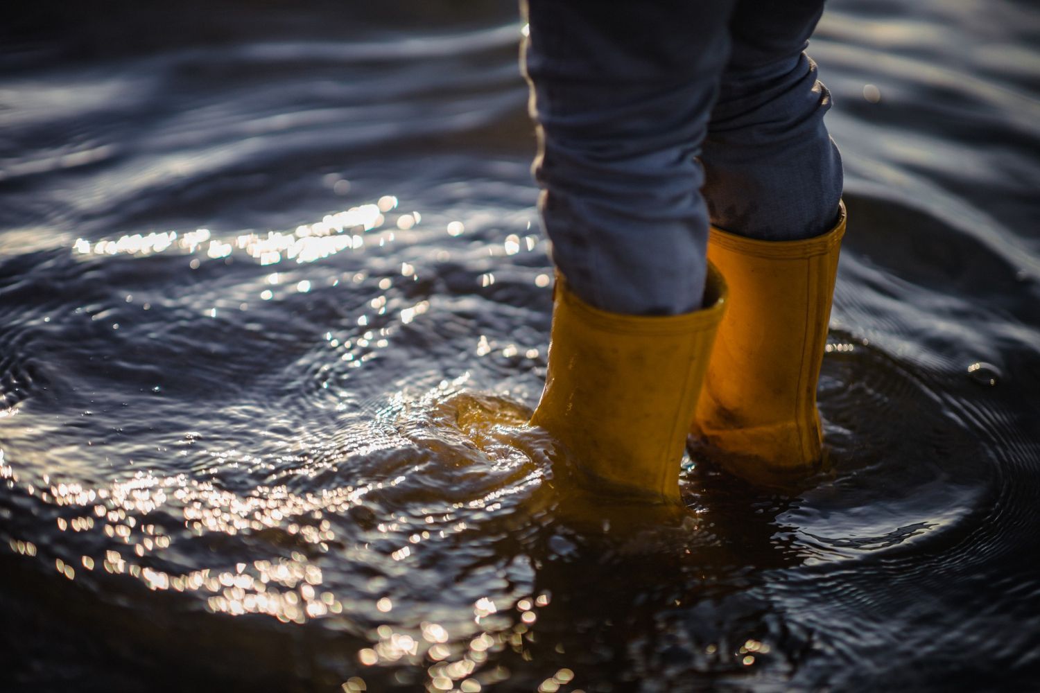 A person wearing yellow rain boots is standing in the water.