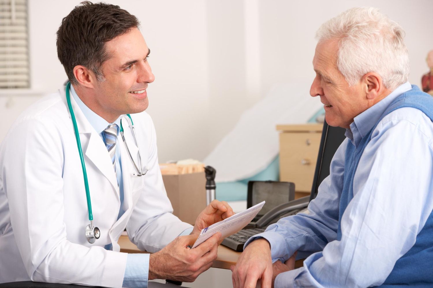 A doctor is talking to an older man in a hospital.
