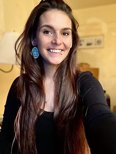A woman with long hair is smiling for the camera while wearing a black shirt and earrings.