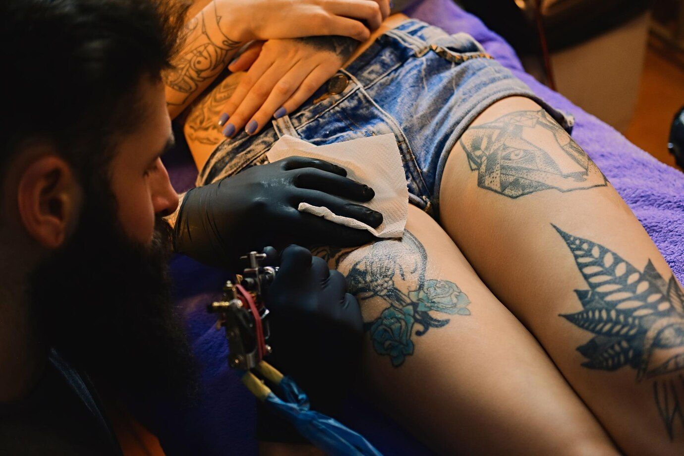 a man is getting a tattoo on a woman 's leg