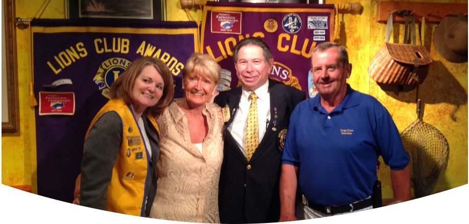 A group of people posing for a picture in front of a banner that says lions club awards