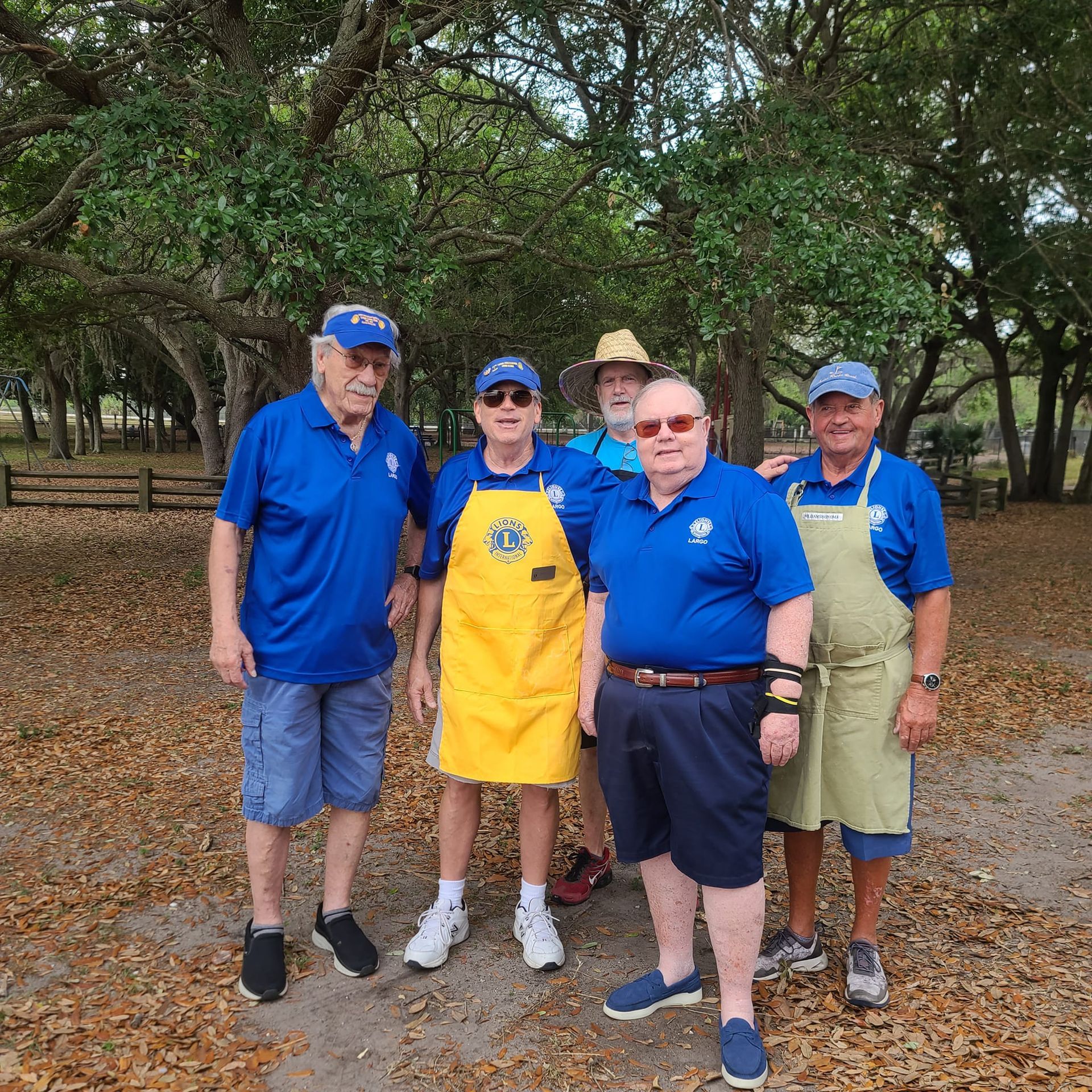 A group of men wearing blue shirts and aprons are posing for a picture.