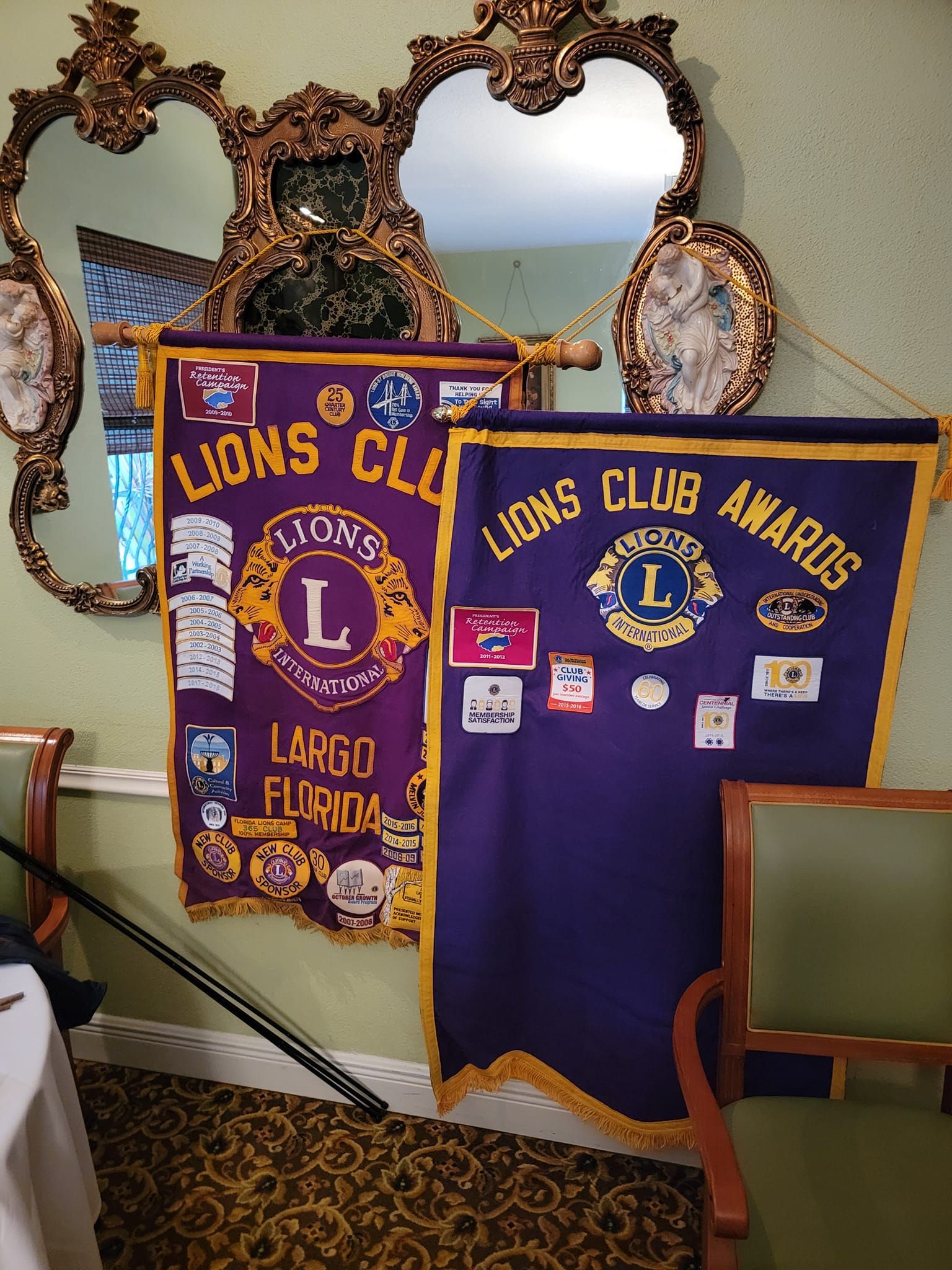 Two lions club banners are hanging on a wall
