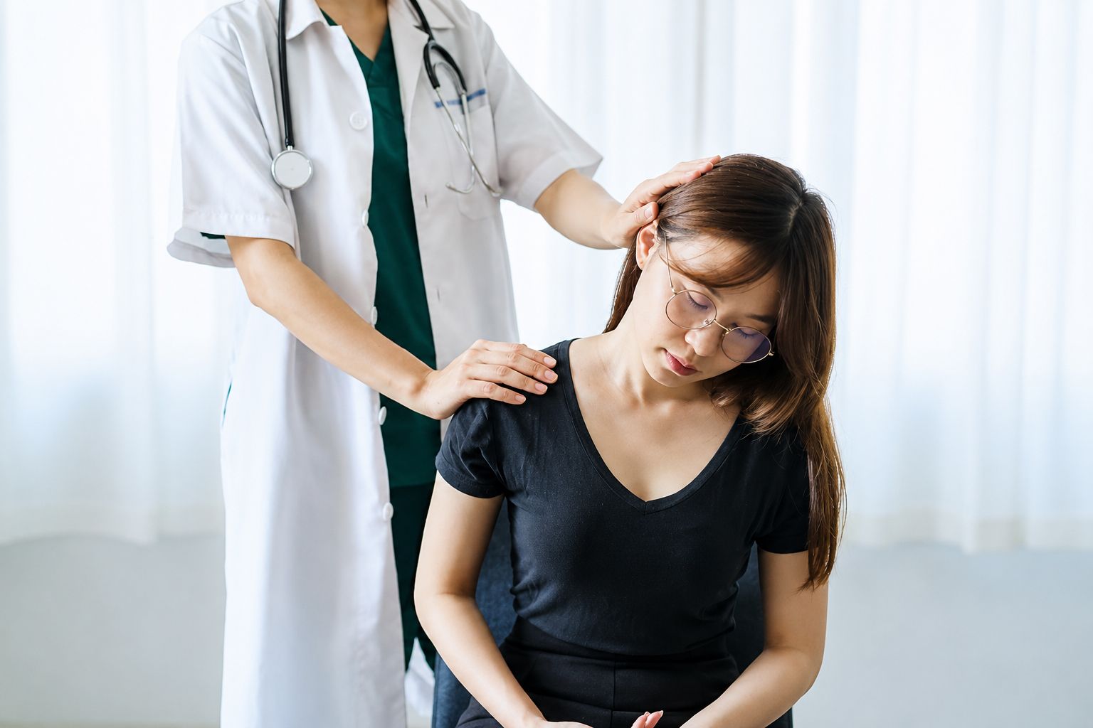 Doctor examining a seated patient’s shoulder in a bright clinic room
