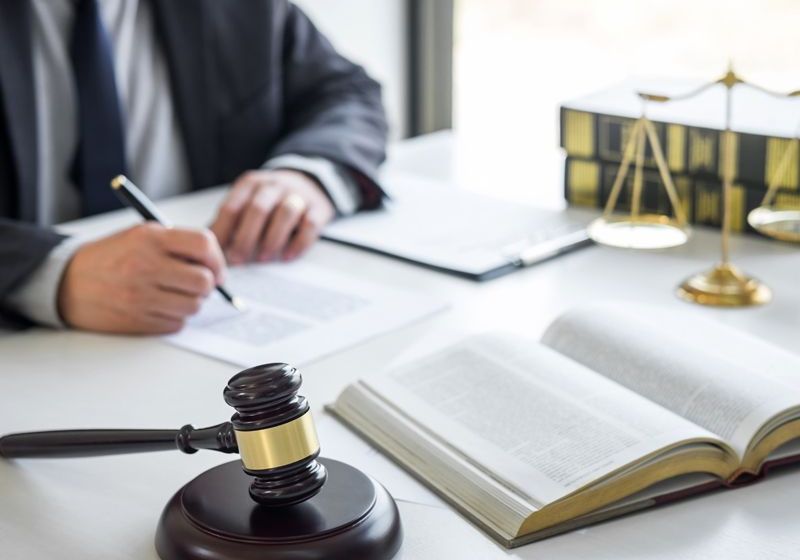 A judge is sitting at a desk with a book and a gavel.