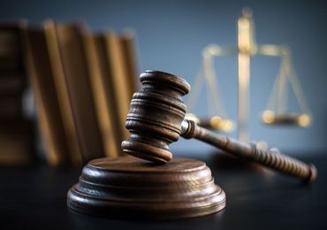 A wooden judge 's gavel and scales of justice are on a table.