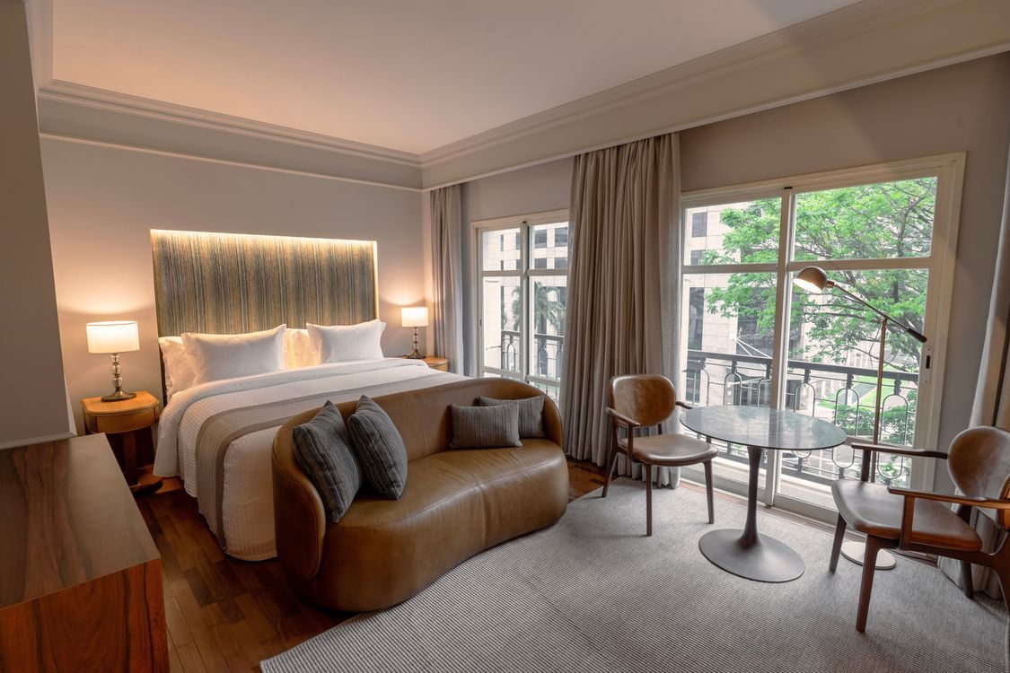 um quarto de hotel com cama, mesa, cadeira e televisão.