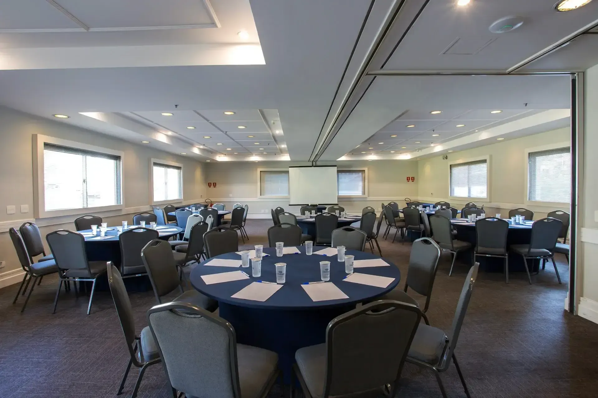 uma grande sala com mesas e cadeiras preparadas para uma reunião