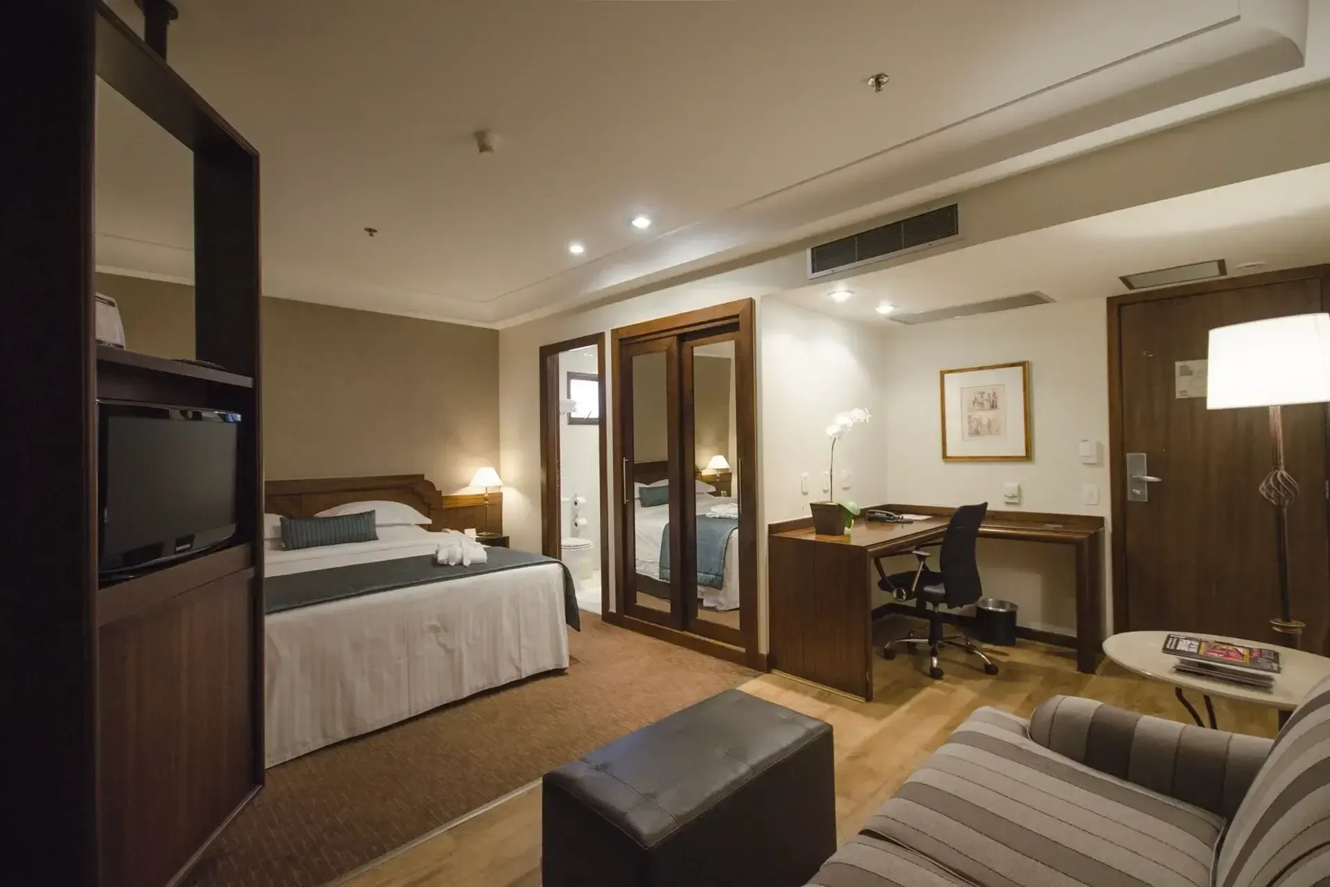um quarto de hotel com cama king size e sofá