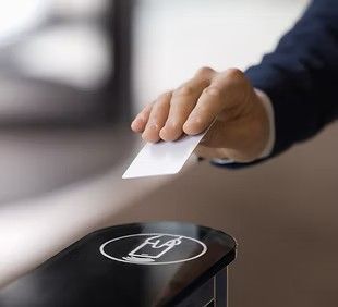 Person's hand with card over a card reader for access control.