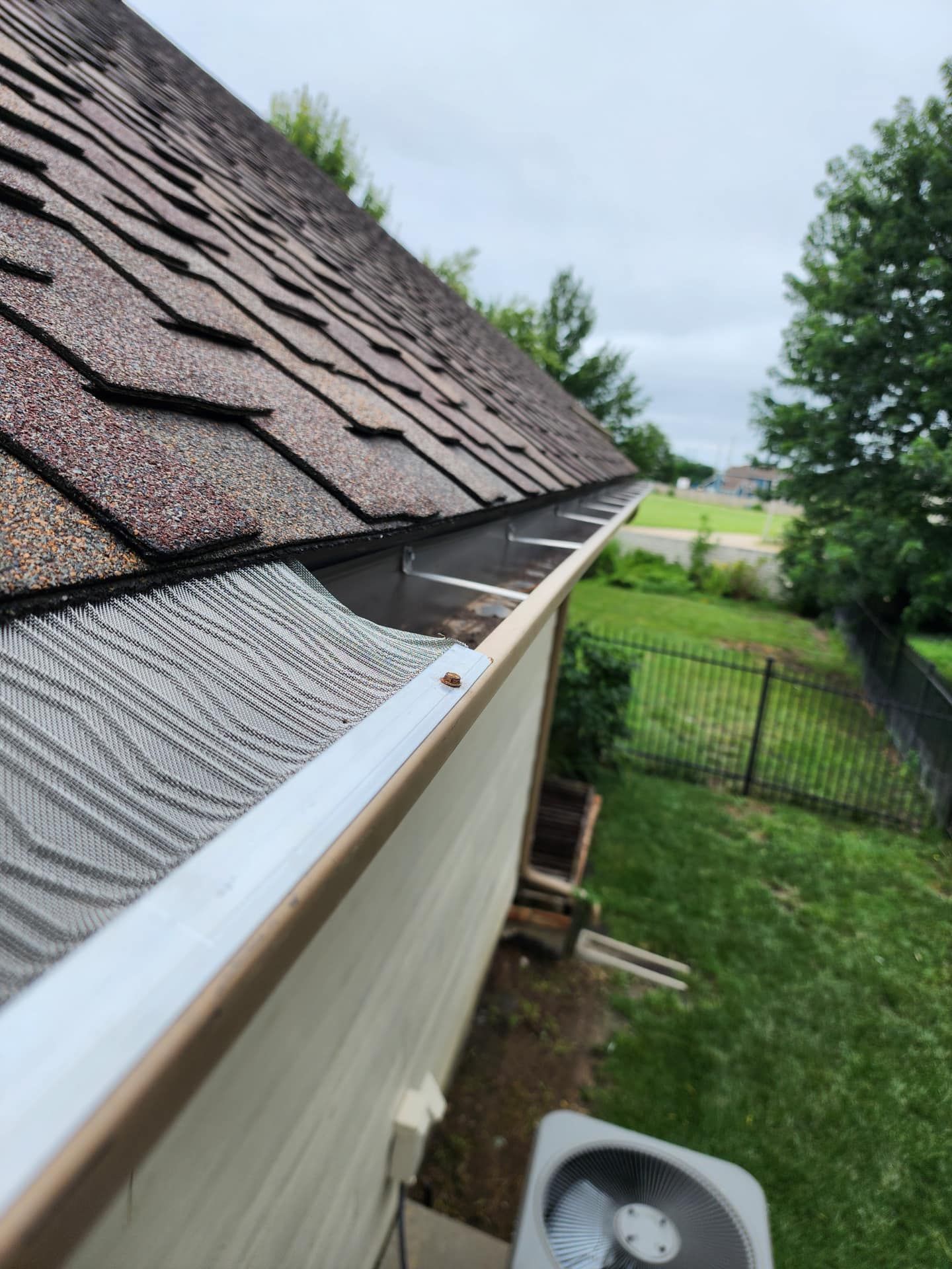A gutter on the side of a house next to an air conditioner.