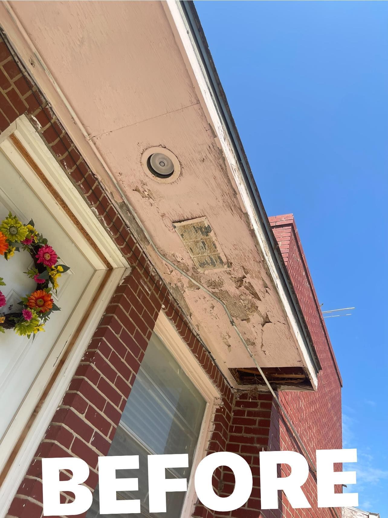 A before picture of a brick building with a wreath on the door