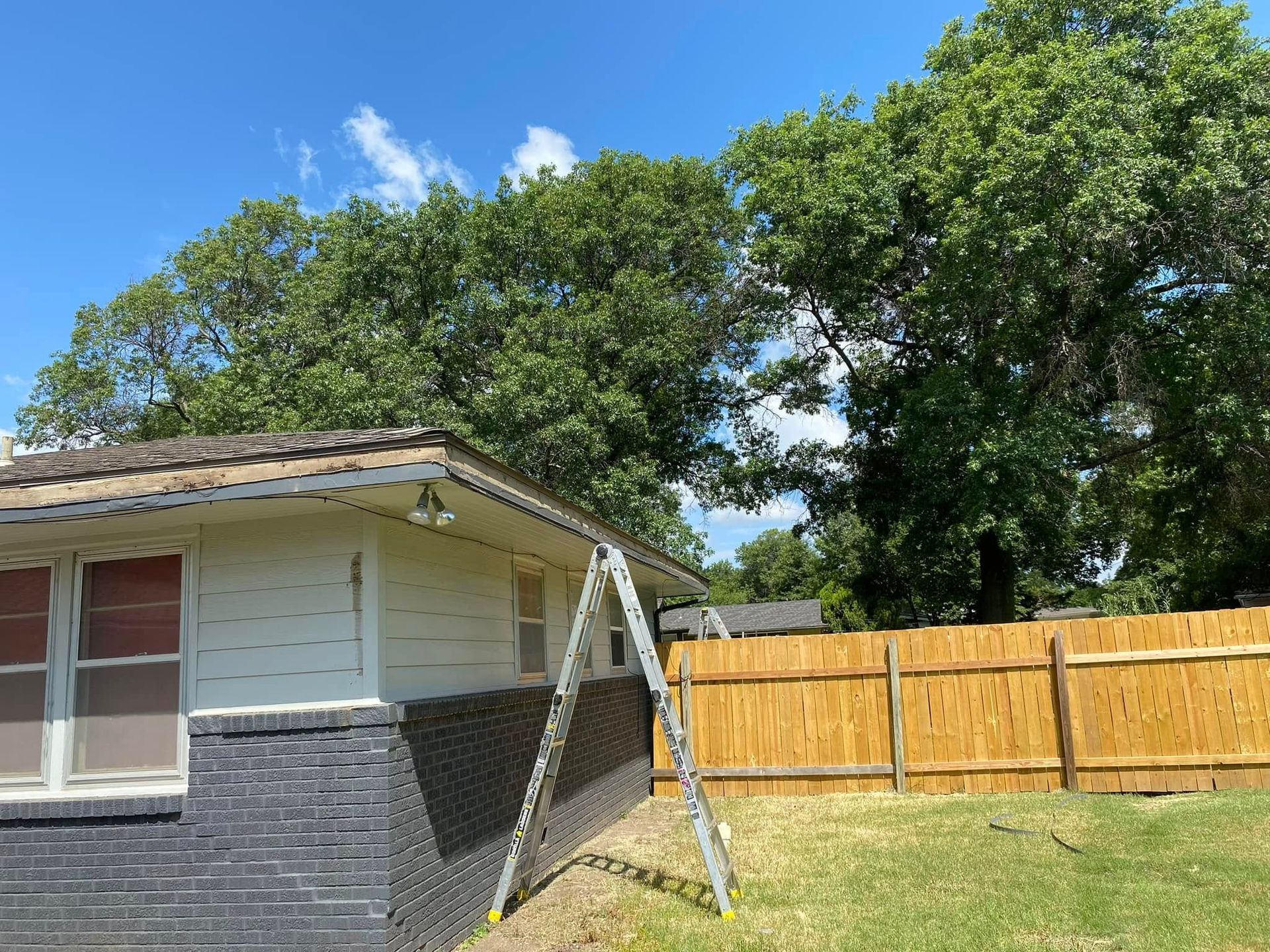 A house with a wooden fence and a ladder in front of it.