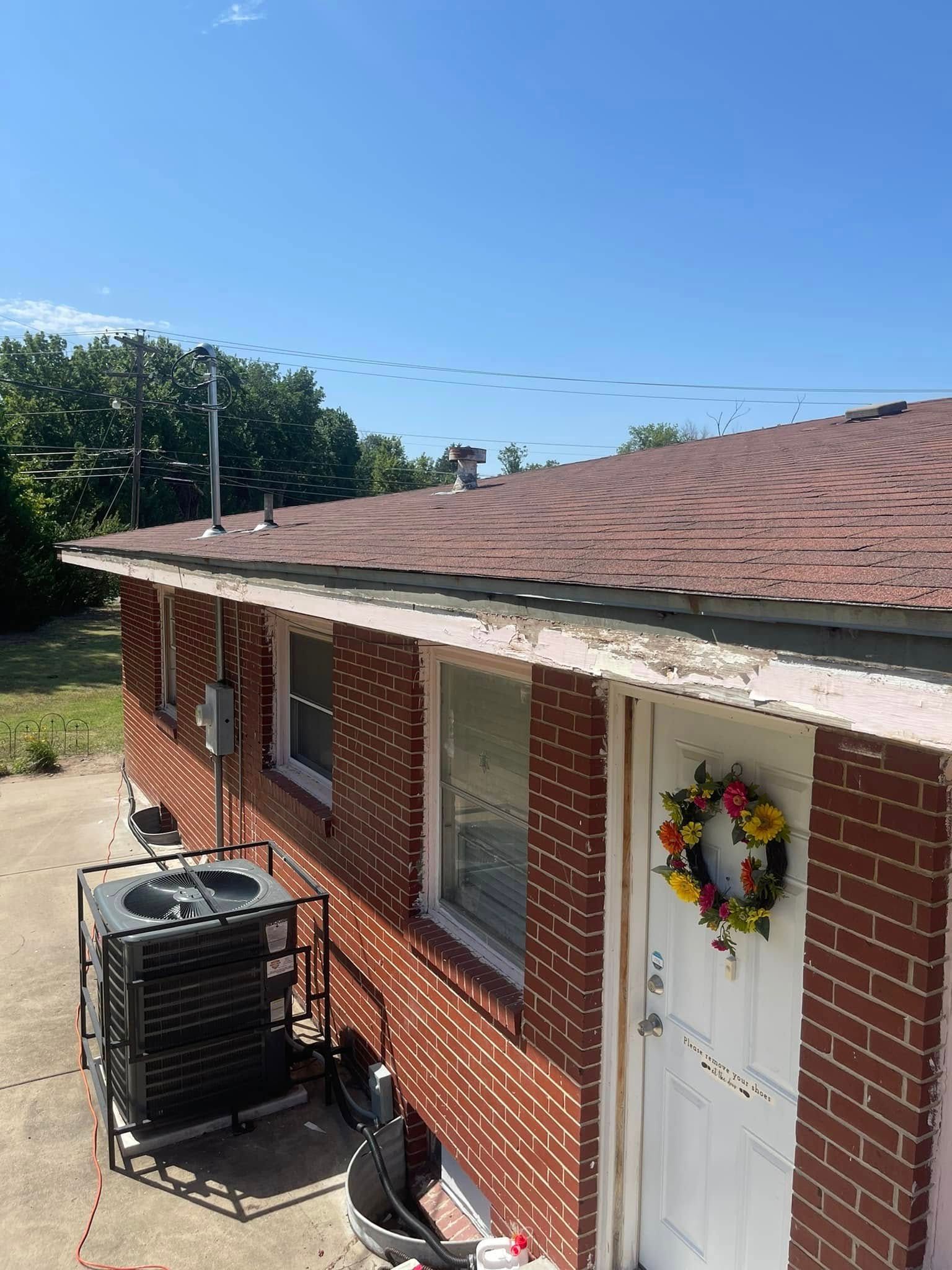 A brick house with a wreath on the door and a roof.